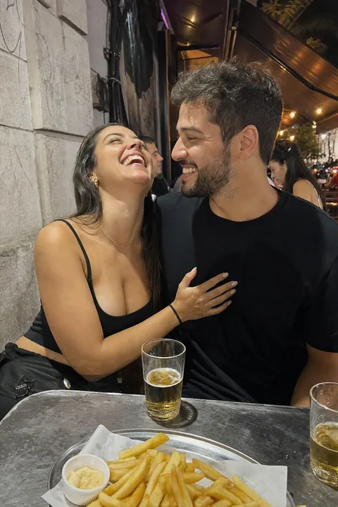 Casal rindo junto num bar de rua à noite